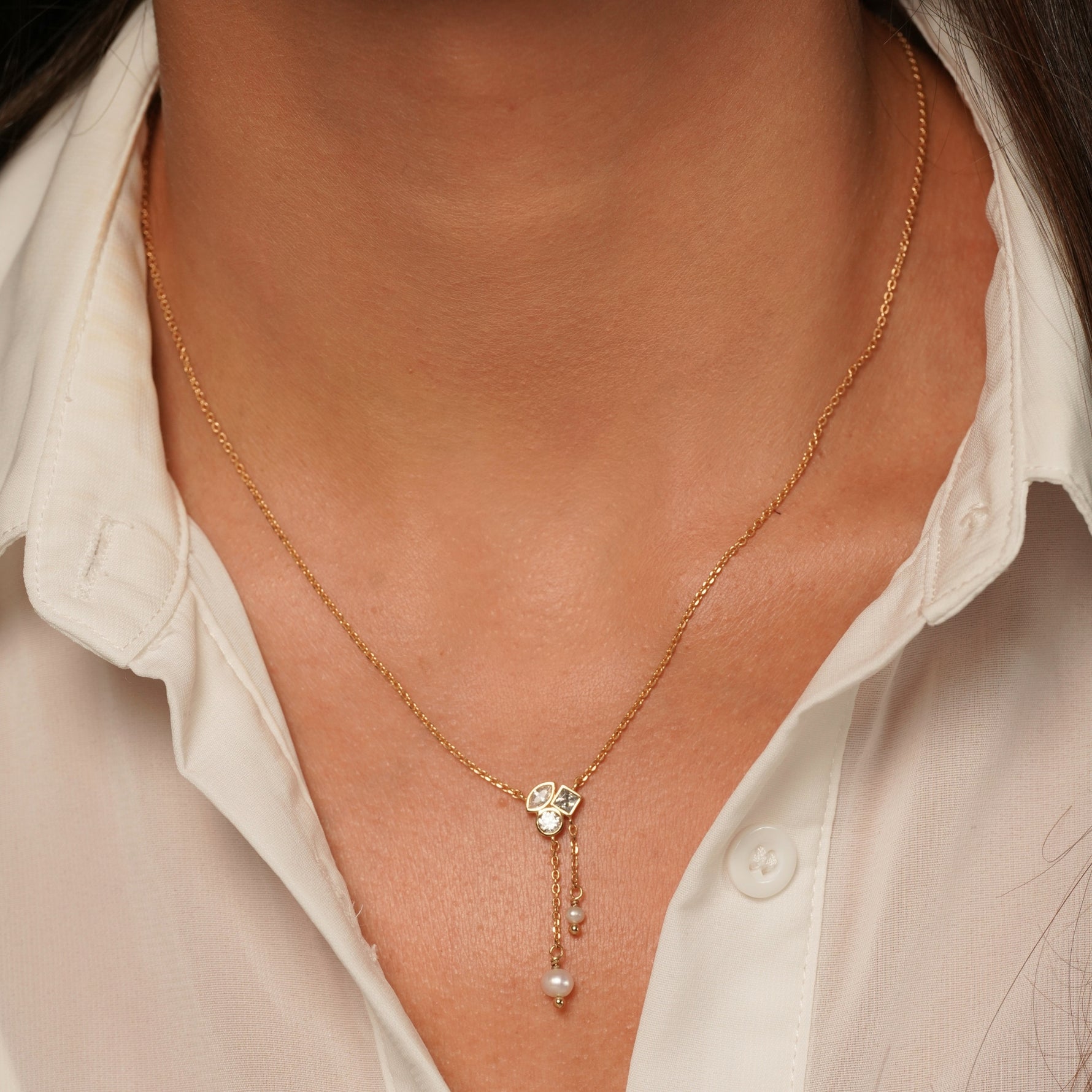 A close-up of a model wearing Better Off Necklace in 18K Gold Plating Featuring Genuine Freshwater Pearl Drops and Mixed-Cut Clear Cubic Zirconia with Delicate Asymmetric Chain Detail | Burren Jewellery
