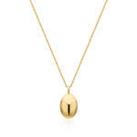 A gold oval locket pendant necklace on a delicate gold chain, presented against a clean white background with a soft reflection below.