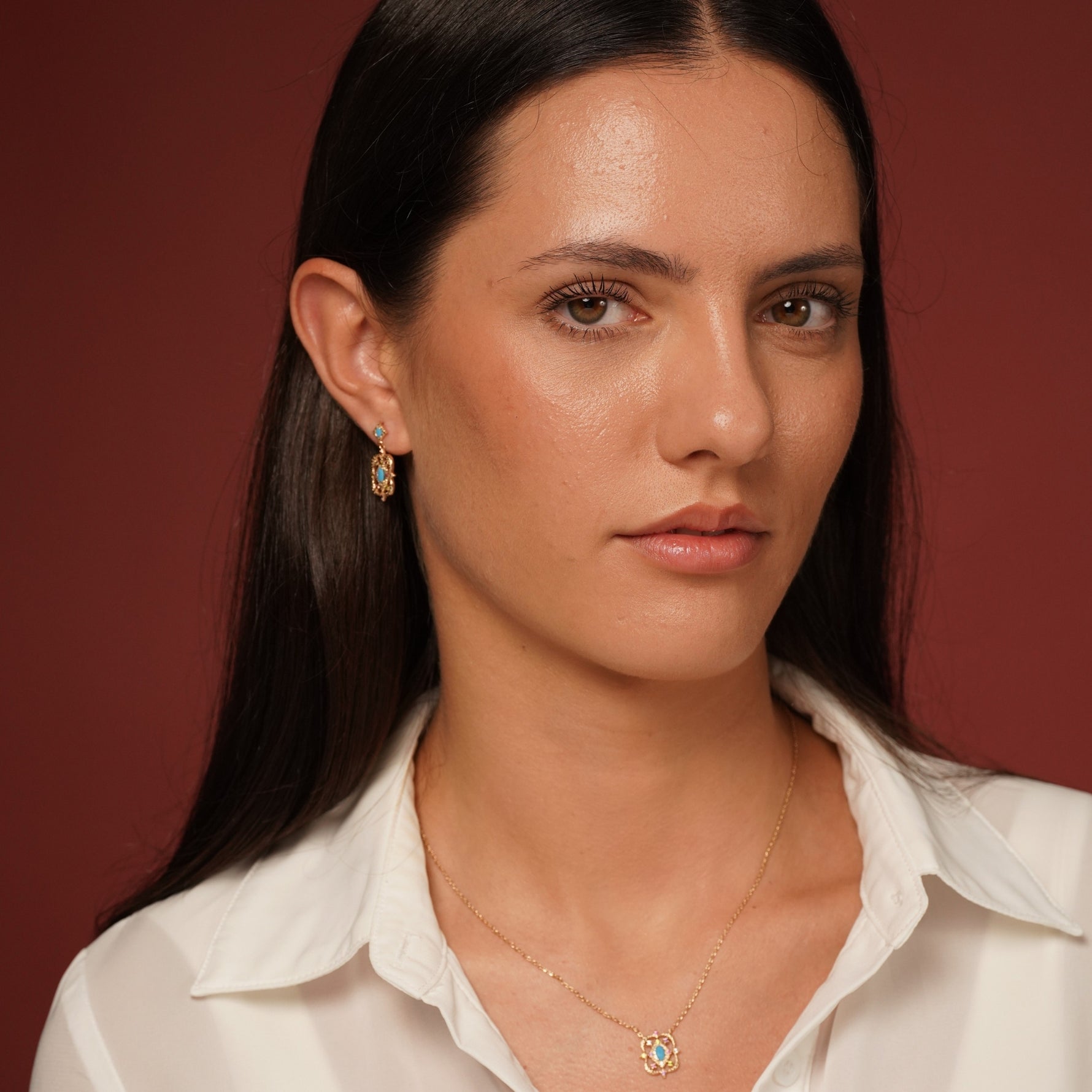 Model Wearing Desert Bloom Earrings in 18K Gold Plating Featuring Turquoise-Coloured Oval Centre Stones with Multicolour Cubic Zirconia in an Intricate Openwork Drop Design | Burren Jewellery