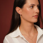 A close-up of a woman wearing Classic Cutness Earrings and Necklaces in 18K Gold Plating Featuring Round, Marquise and Pear Cut Cubic Zirconia Drop Earrings | Burren Jewellery
