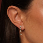 A close-up of a person's ear wearing Classic Cutness Earrings in 18K Gold Plating Featuring Round, Marquise and Pear Cut Cubic Zirconia Drop Earrings | Burren Jewellery