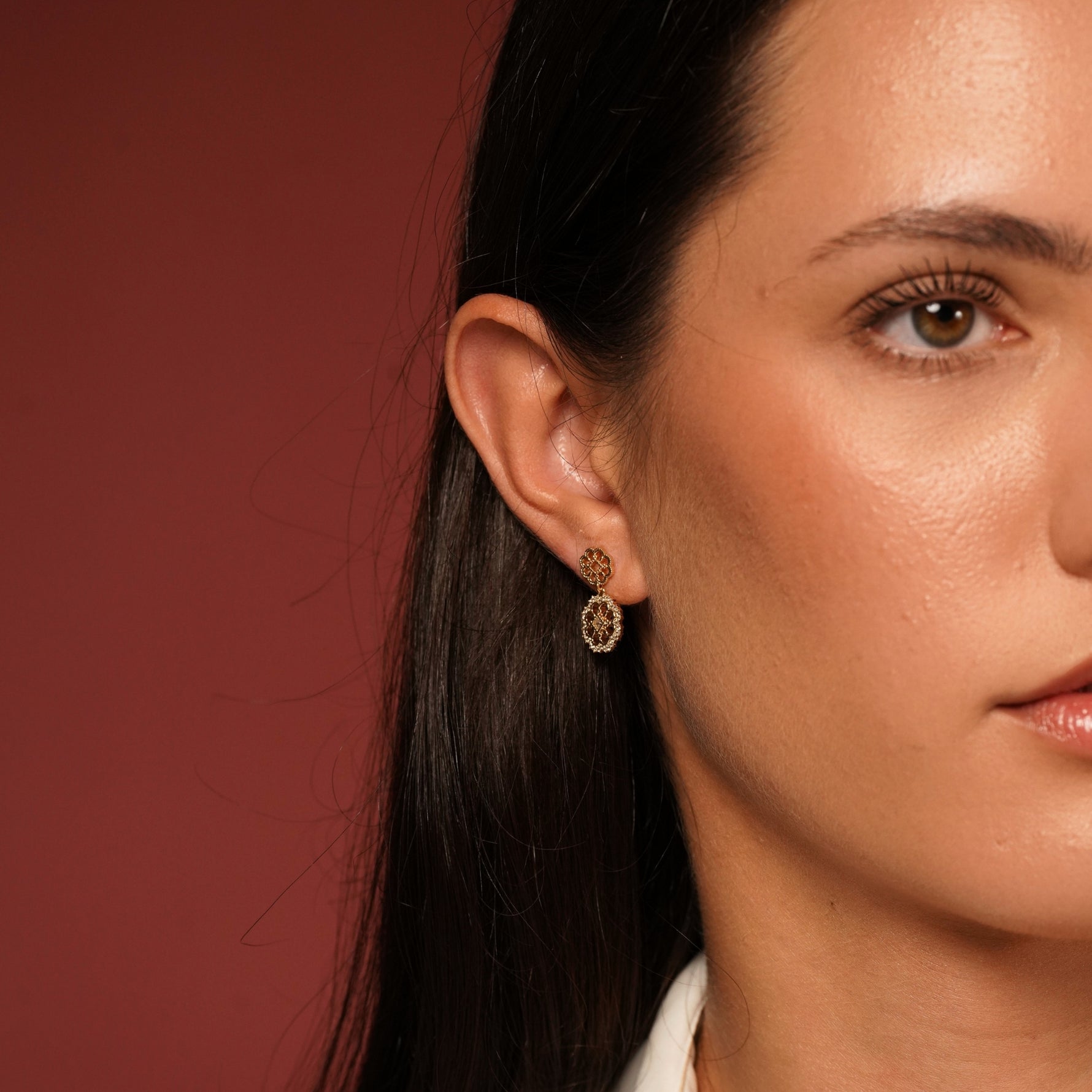 A close-up of a woman's ear and side profile wearing Flower Garden Earrings in 18K Gold Plating Featuring Floral Drop Earrings with Cubic Zirconia | Burren Jewellery