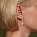 Model wearing the Cassis gold plated earring with pearl and spiral shell charm