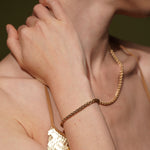 Model wearing the Sweet Echo gold plated wheat chain bracelet, close up with matching necklace