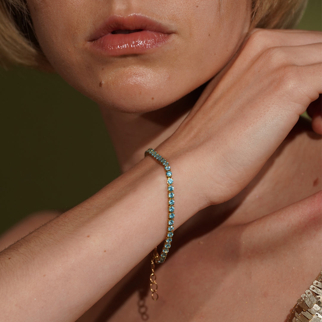 A close-up lifestyle shot of a model wearing Glamour 18K Gold Plated Tennis Bracelet with Light Blue Cubic Zirconia | Burren Jewellery