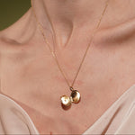 A close-up of a models's neck and chest wearing Little Moment Locket Pendant in 18K Gold Plating Featuring a Round Opening Locket with Cubic Zirconia Star Detail | Burren Jewellery