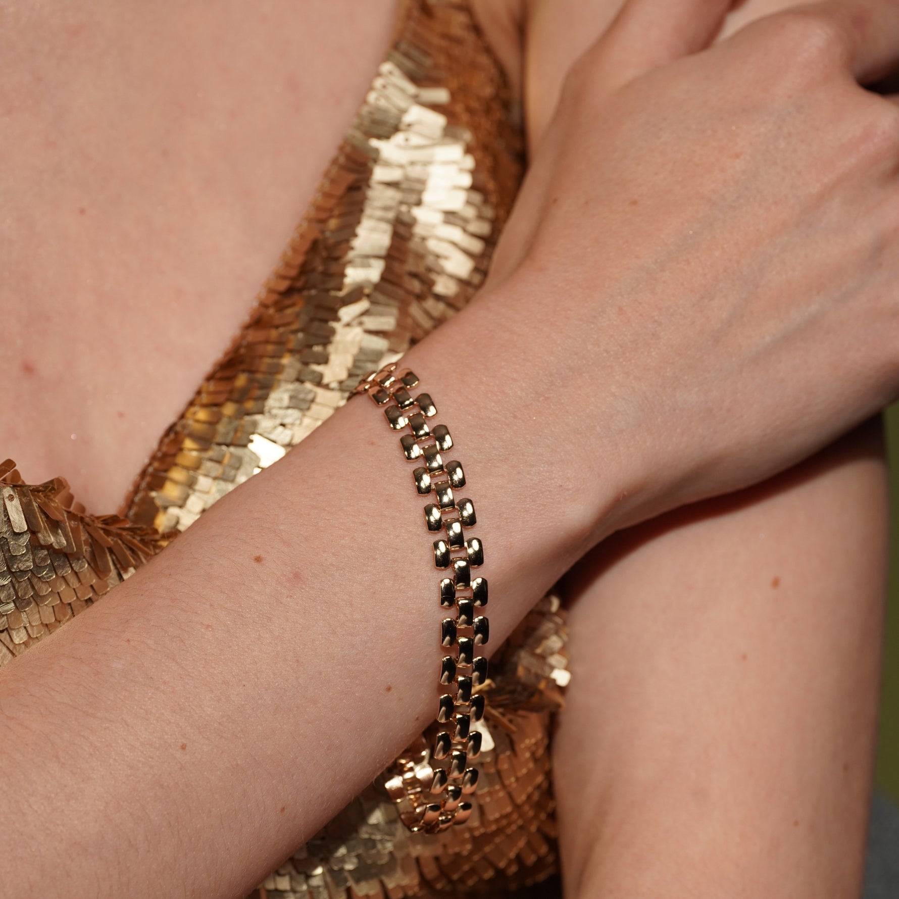 Model wearing the Love Me Like You Do gold plated panel bracelet flat against the wrist with a gold sequin dress