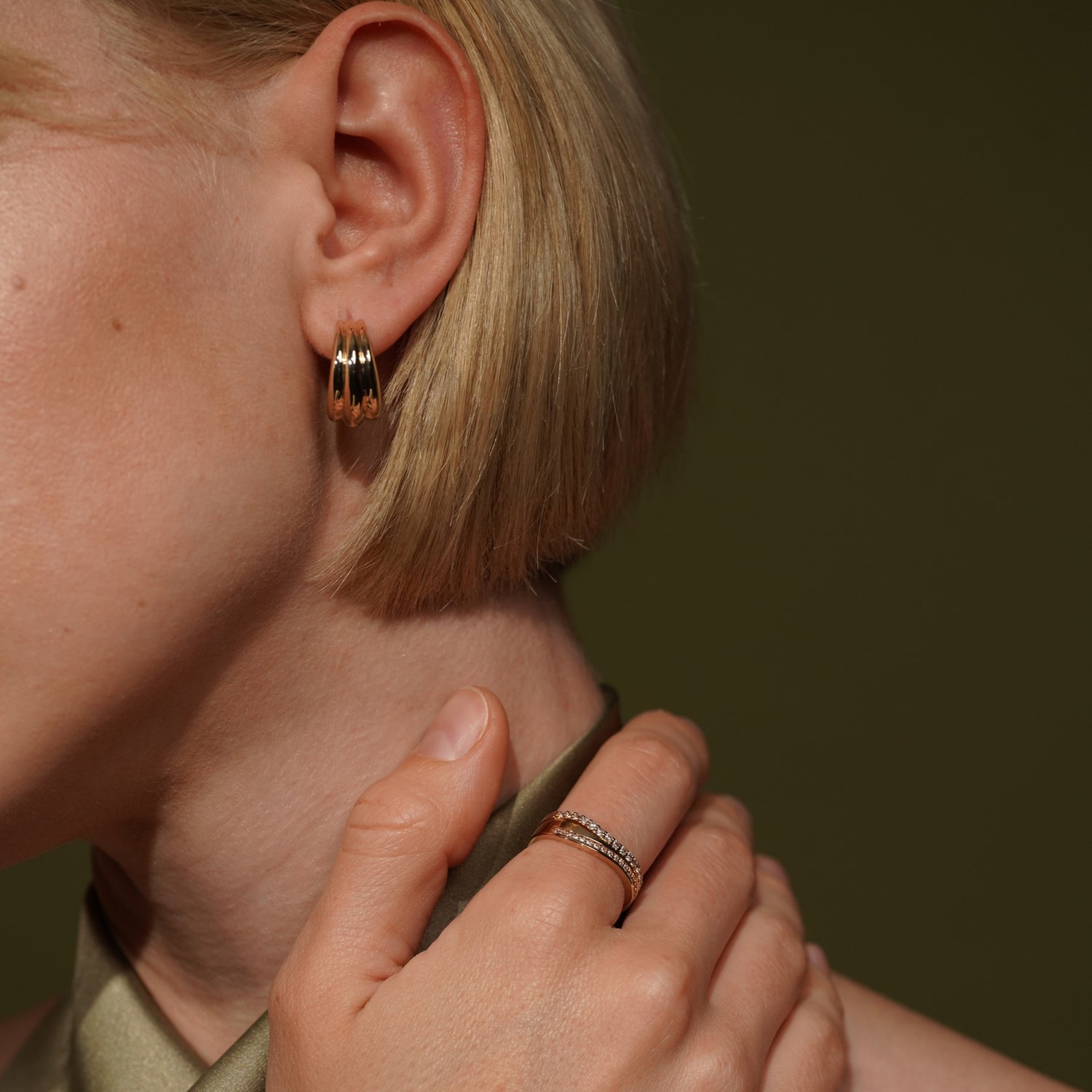 Close-up of a model wearing a small gold hoop earring and Stacked Feeling Lucky and Illumination 18K Gold Plated Pavé Cubic Zirconia Rings | Burren Jewellery