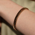 A close-up of model's wrist wearing Paper Heart Chain 18K Gold Plated Chunky Flat Link Bracelet | Burren Jewellery
