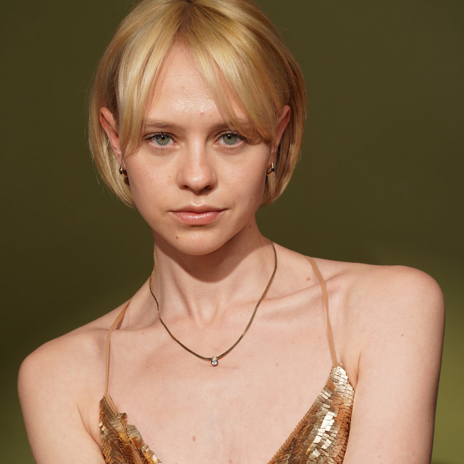 A close-up portrait of a Model wearing Date Night Necklace in 18K Gold Plating Featuring a Bezel-Set Pear Cut Clear Cubic Zirconia Pendant on a Herringbone Snake Chain | Burren Jewellery