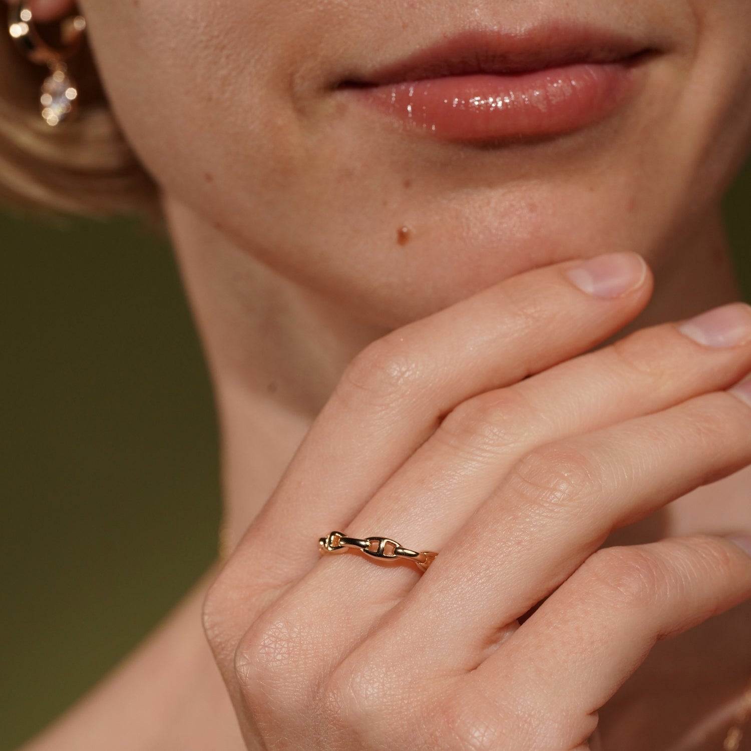 A close-up of a person's hand and lower face wearing Linked Horizons Ring in 18K Gold Plating Featuring a Modern Interlocking Chain Link Design | Burren Jewellery