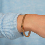 Empress Thread gold plated mesh bracelet worn on a wrist with a pale blue knit jumper