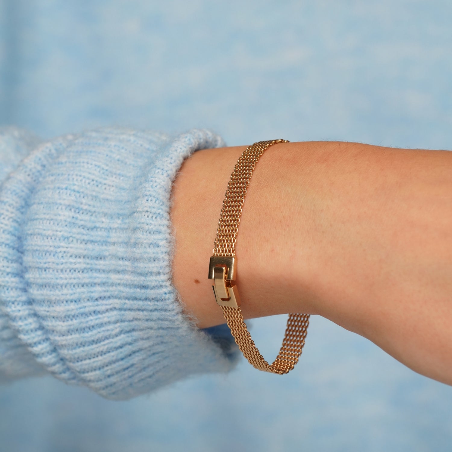 Empress Thread gold plated mesh bracelet worn on a wrist with a pale blue knit jumper