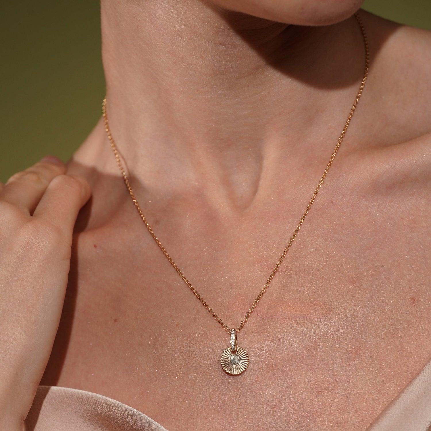 A close-up of a model's wearing the Radiance Pendant Necklace in 18K Gold Plating Featuring an Engraved Sunburst Pendant with Pavé Crystal Bail | Burren Jewellery
