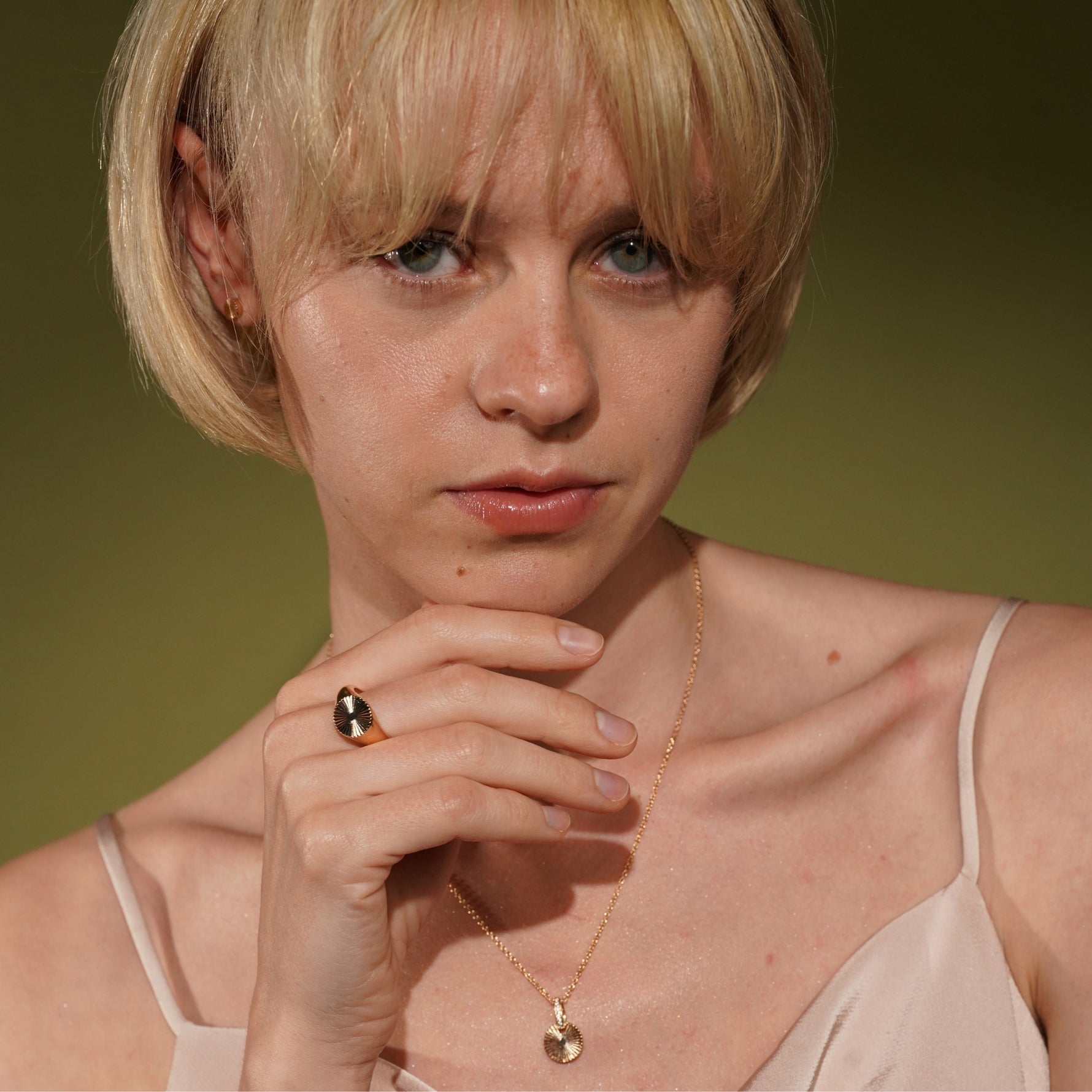 A close-up portrait of a model wearing the Radiance Ring, necklace and earrings in 18K Gold Plating Featuring an Engraved Sunburst Motif | Burren Jewellery