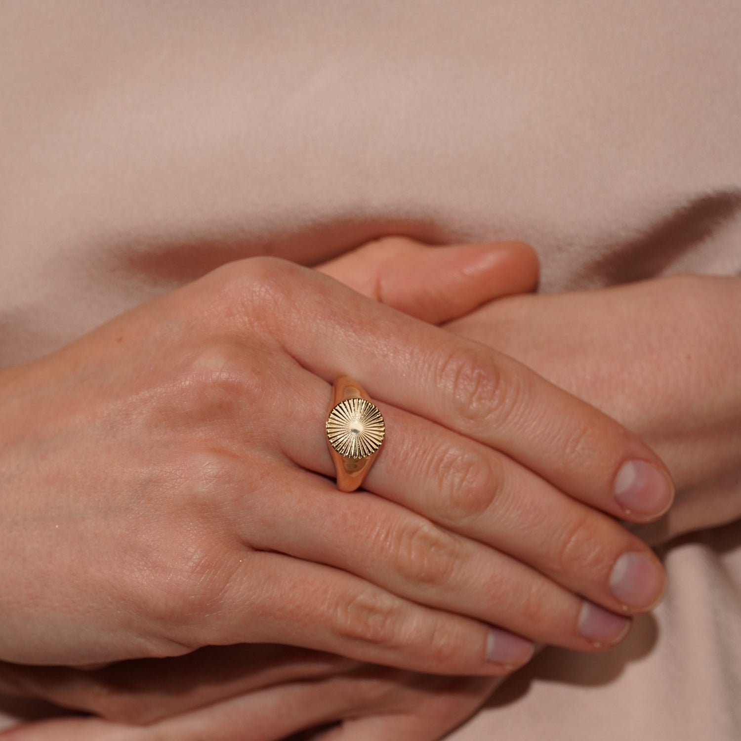 A close-up of a models's hands wearing Radiance Ring in 18K Gold Plating Featuring a Classic Signet Design with an Engraved Sunburst Motif | Burren Jewellery