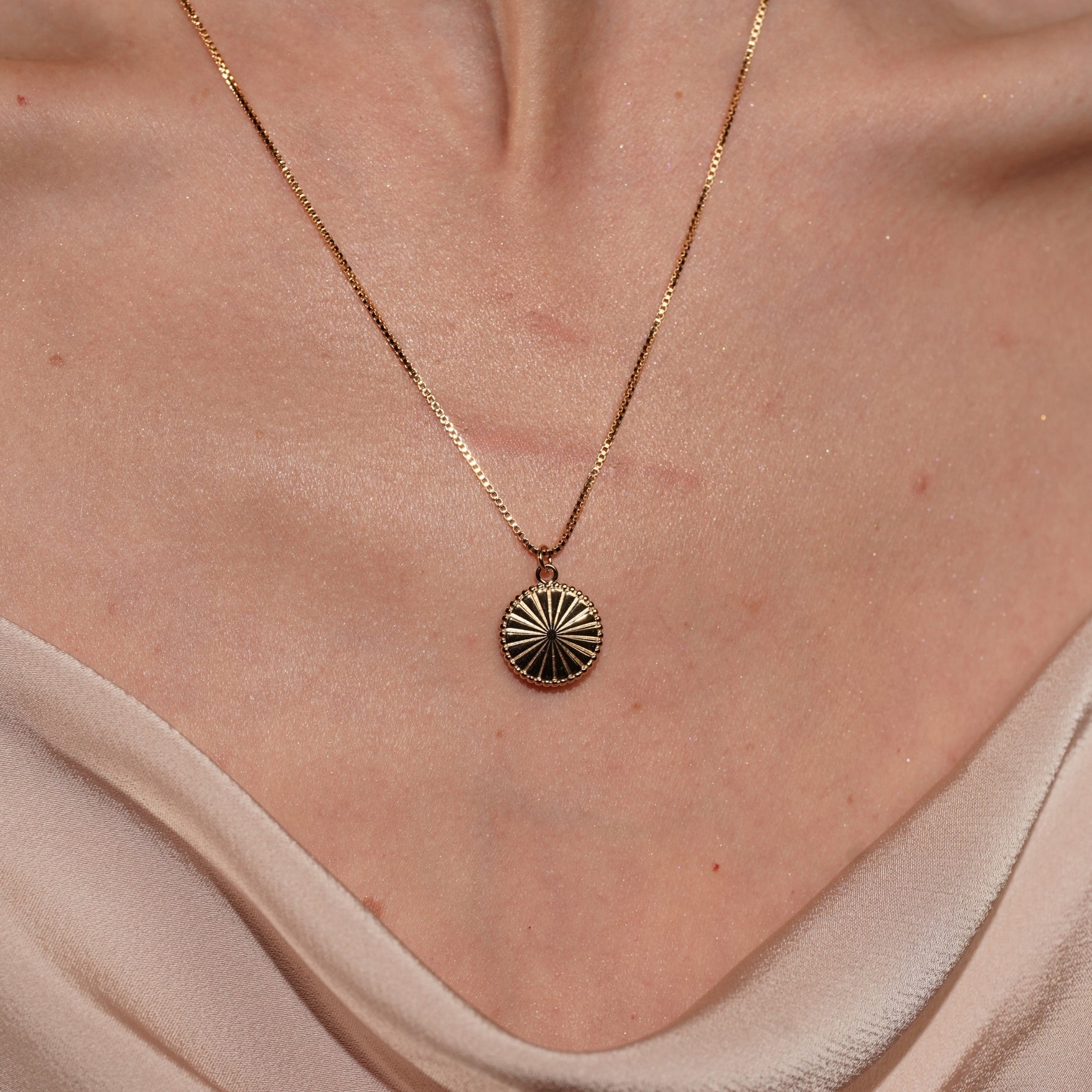Model wearing Noble Pendant Necklace in 18K Gold Plating Featuring an Engraved Sunburst Circular Pendant with Beaded Border on a Fine Box Chain | Burren Jewellery