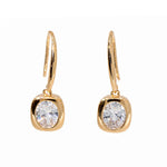 A pair of gold drop earrings with a rounded bezel setting holding a clear round-cut gemstone, suspended from curved hook wires, shown on a plain white background.