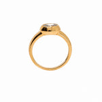 A gold ring with a bezel-set clear gemstone, shown from a top-down view on a plain white background.