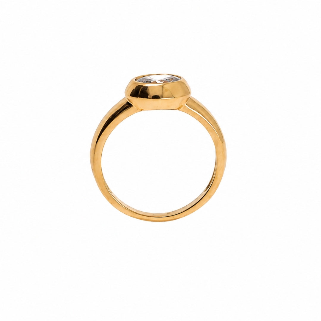 A gold ring with a bezel-set clear gemstone, shown from a top-down view on a plain white background.