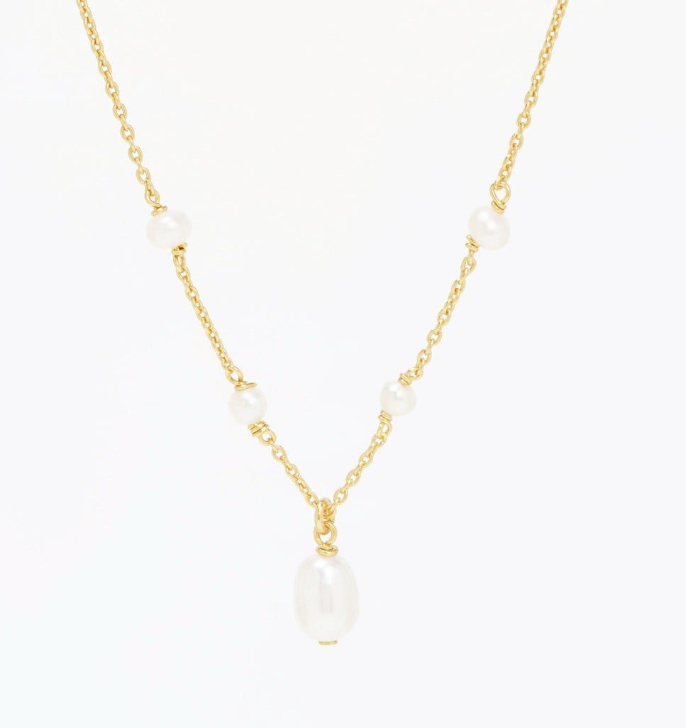 Tidekiss gold plated necklace laid flat, four station pearls and a larger centre drop natural pearl