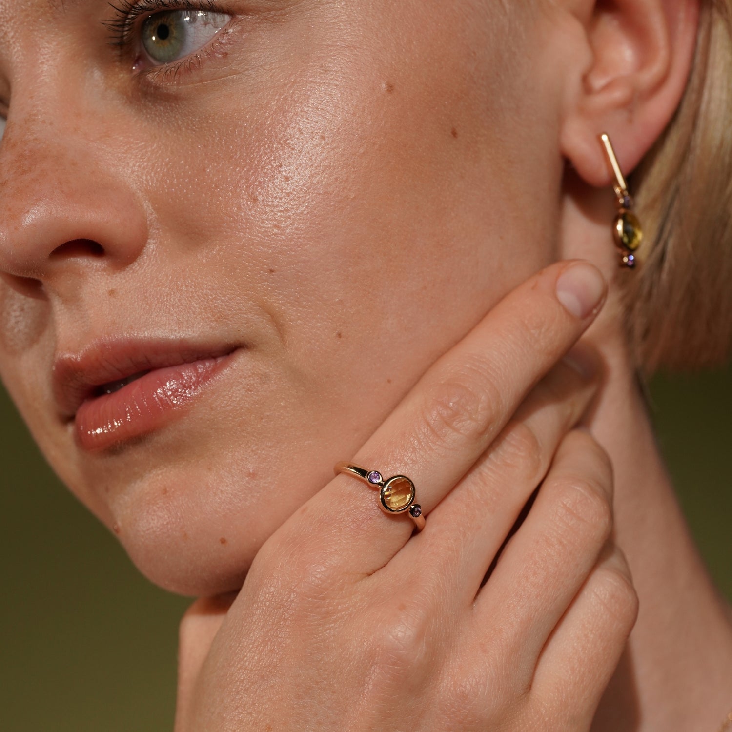 A close-up lifestyle shot of a model wearing Lingering Light Ring in 18K Gold Plating Featuring an Oval Citrine-Coloured Cubic Zirconia with Round Amethyst-Coloured Cubic Zirconia Accents | Burren Jewellery