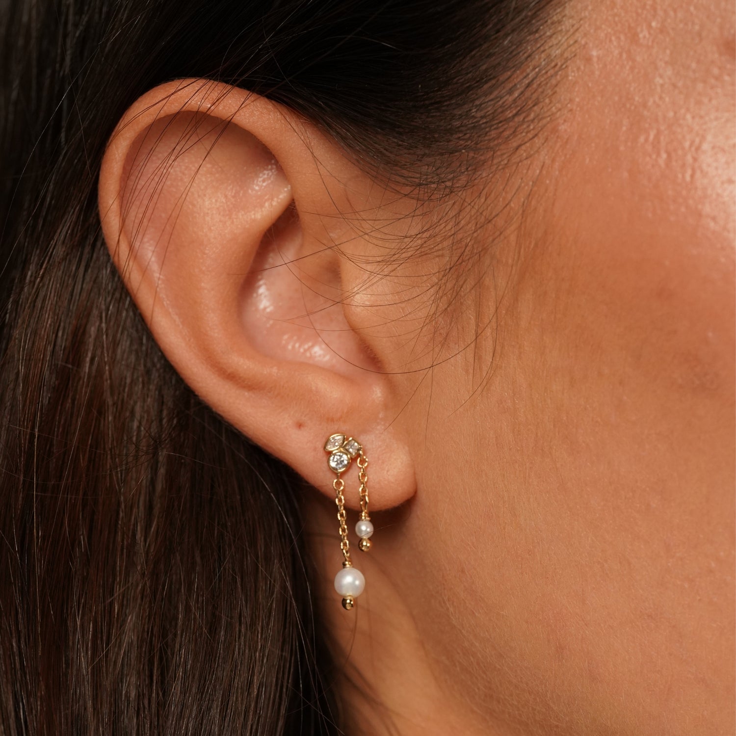 A close-up of a person's ear wearing Better Off Earrings in 18K Gold Plating Featuring Genuine Freshwater Pearl Drops and Mixed-Cut Clear Cubic Zirconia with Delicate Double Chain Detail | Burren Jewellery