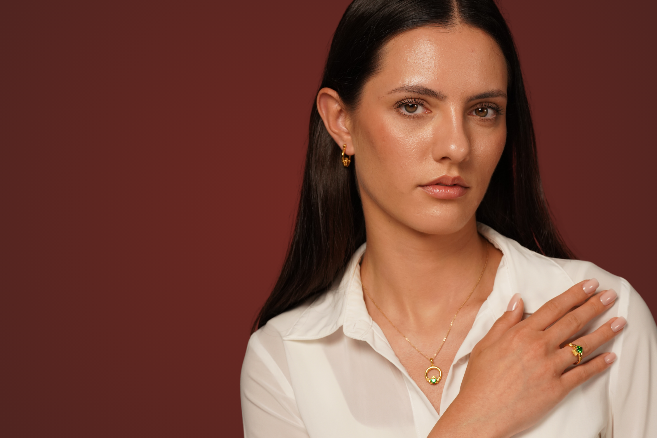 Model wearing gold jewellery from the Burren Jewellery Claddagh Collection, featuring green stone Claddagh-inspired designs.