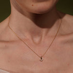 A close-up of a model's neck and chest wearing a delicate gold plated hexagonal pendant necklace with cz stone detail