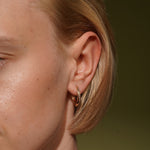 Model wearing the Soft Embrace gold plated pavé hoop earring close to the earlobe