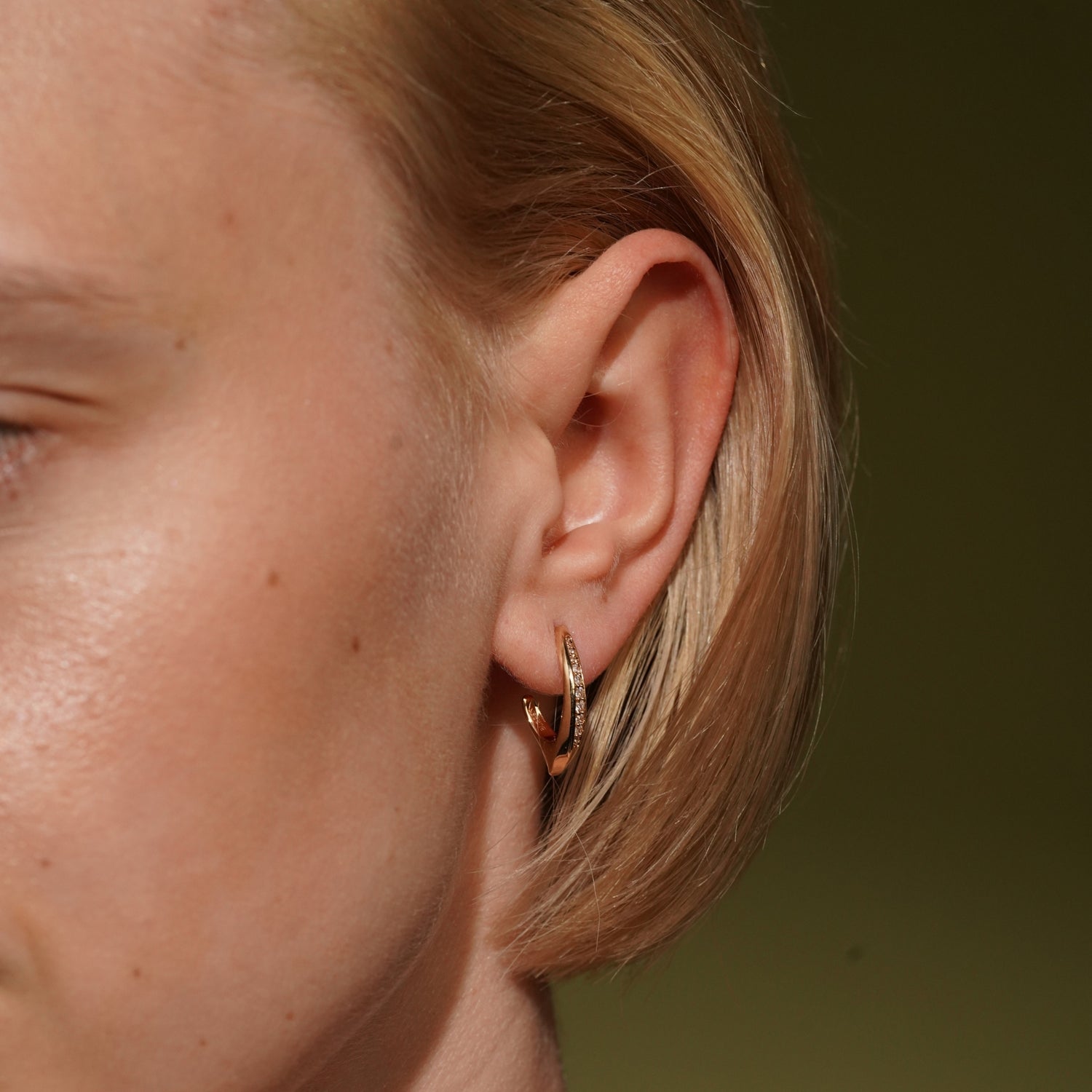 Model wearing the Soft Embrace gold plated pavé hoop earring close to the earlobe