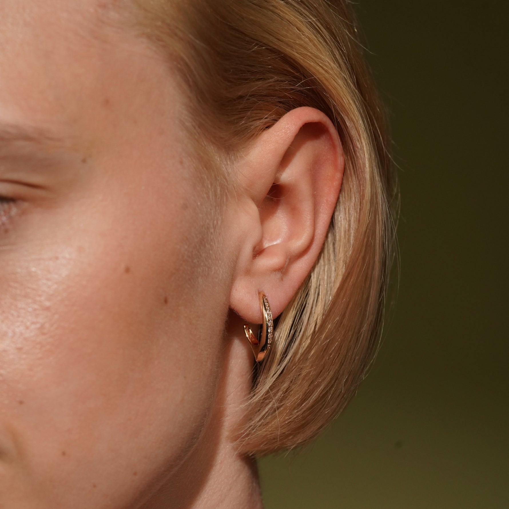 Model wearing the Soft Embrace gold plated pavé hoop earring close to the earlobe
